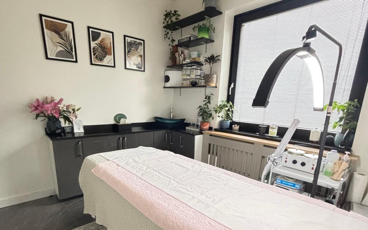 The treatment room at Ela Aesthetic Studio with the facial bed, magnifying lamp and botanical prints